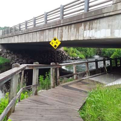 Along the Iron River shelter under the bridge on the Apple Blossom Trail. Just down the trail is the The Tailings Disc Golf Course.