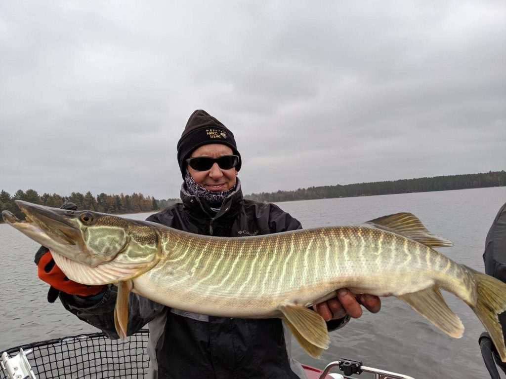 Person holding a large fish on a lake.