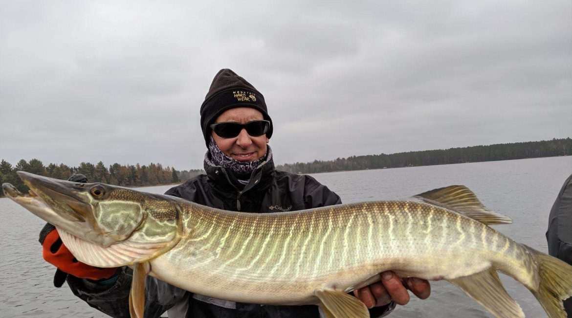 Person holding a large fish on a lake.
