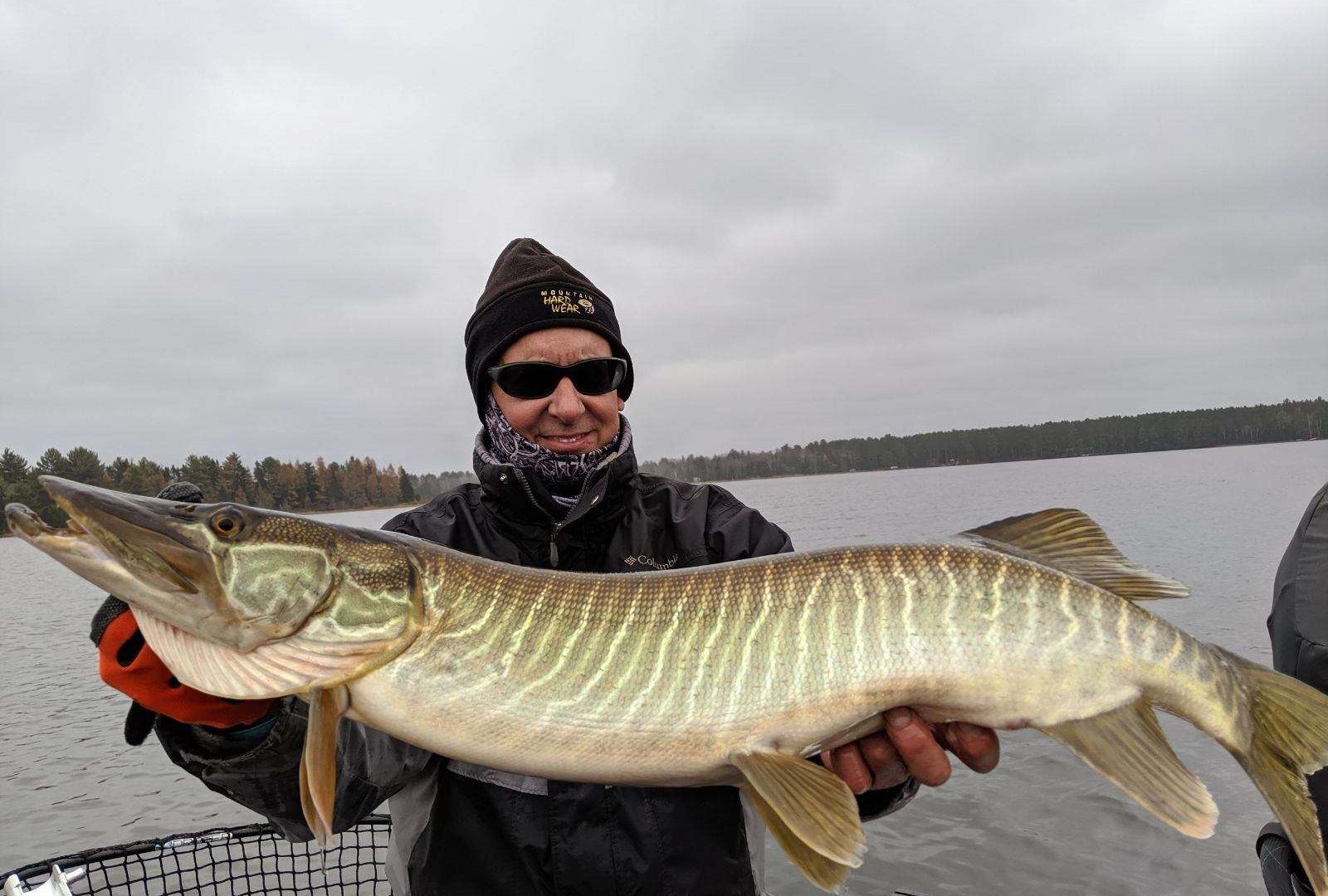 Person holding a large fish on a lake.