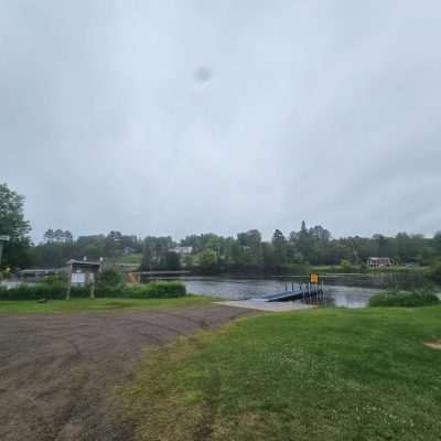 Lakeside park with boat ramp and signs.