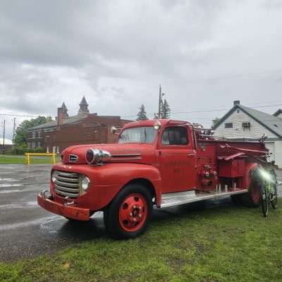 Vintage red firetruck parked on rainy day.