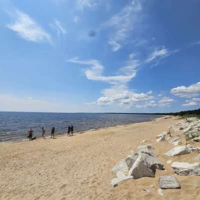 People walking along a sunny sandy beach.