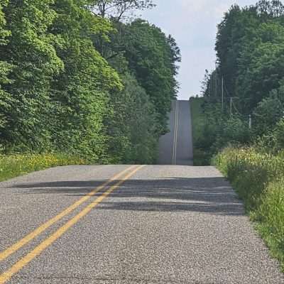 Rural road through forested landscape.