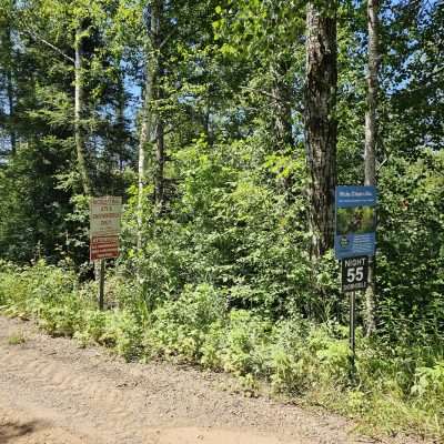 Nicole Trail signs surrounded by dense green forest