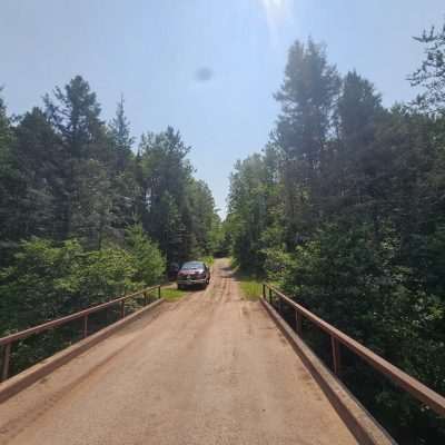 Red truck on a forest trail bridge