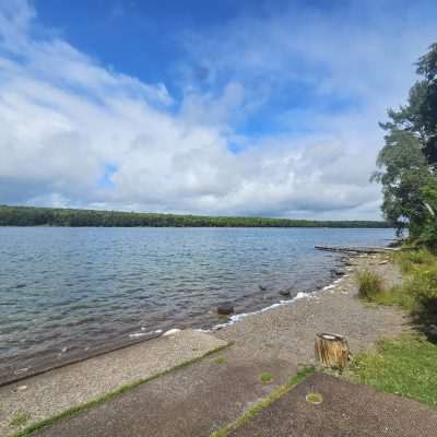 Calm lake with cloudy sky and forested shore.