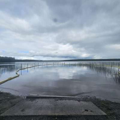 Serene lake with cloudy sky and yellow barrier