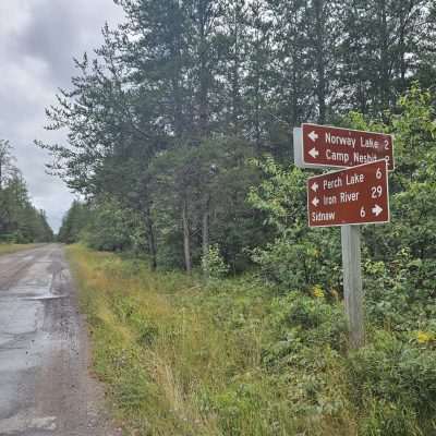 Roadside sign with directions to lakes and locations.