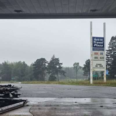 Abandoned gas station with overgrown weeds.