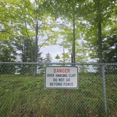 Danger sign on a fence near cliff.