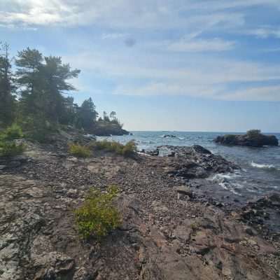 Rocky lake shoreline under partly cloudy sky