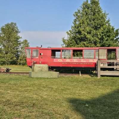 Red railroad car in grassy field.