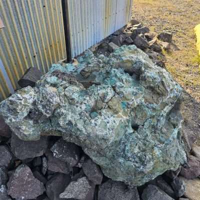 Large copper boulder beside corrugated metal building. Donated by Jim Vivian Jr and Sr.