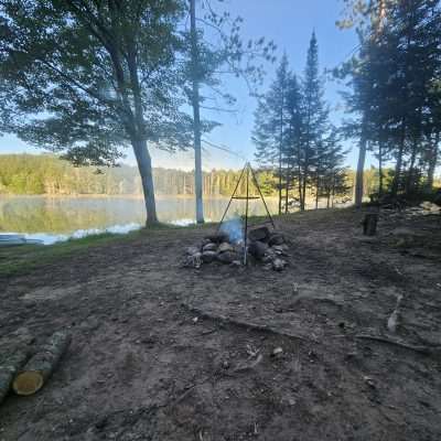 Lakeside campsite with campfire near paddleboat.