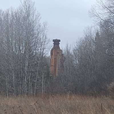Old brick tower behind leafless trees in fall